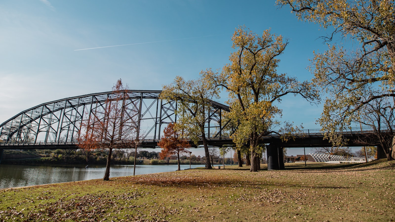 A steel truss bridge crossing a river, framed by autumn trees