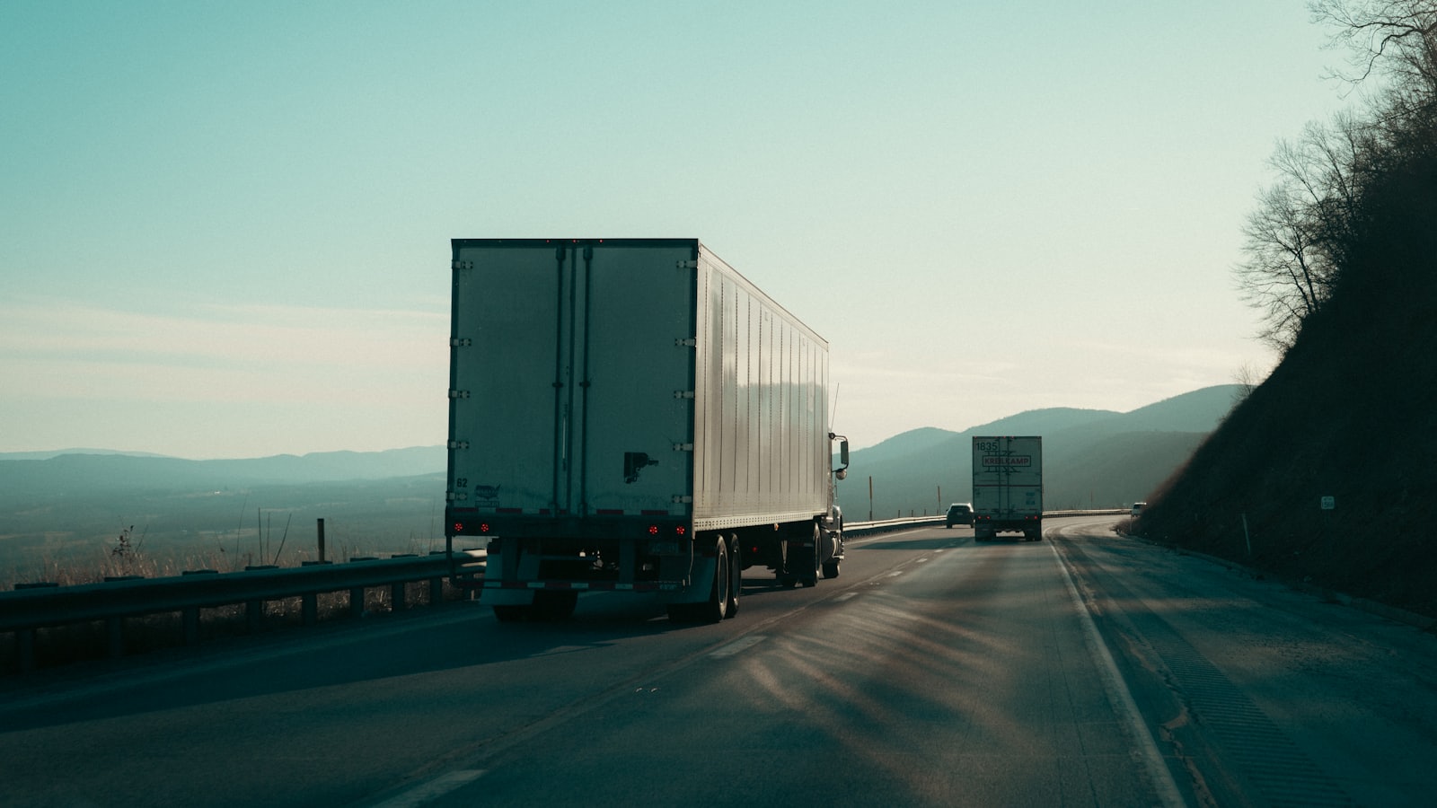 Two semi-trucks hauling freight along a highway