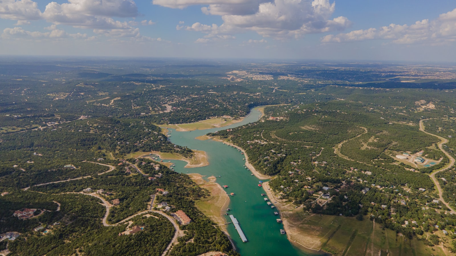 An aerial view of a Hill Country reservoir winding past lakeside homes